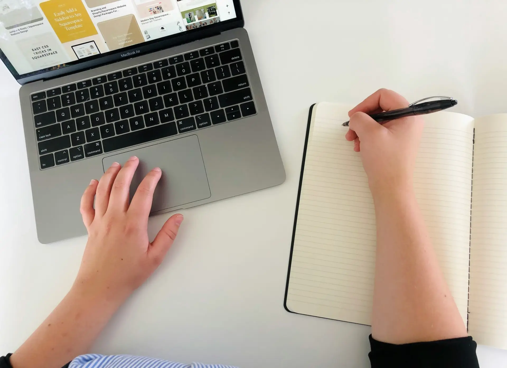 A writer taking notes beside a laptop keyboard